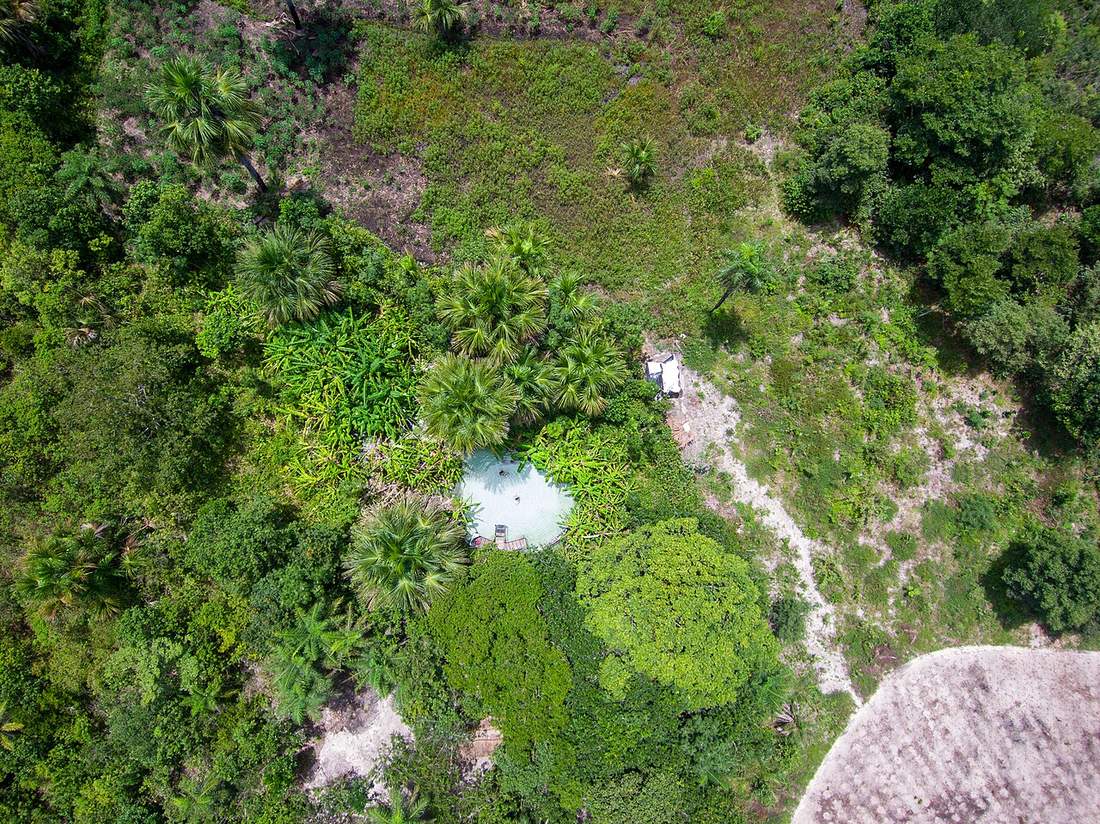 Fervedouro turquesa visto desde el aire, rodeado de palmeras