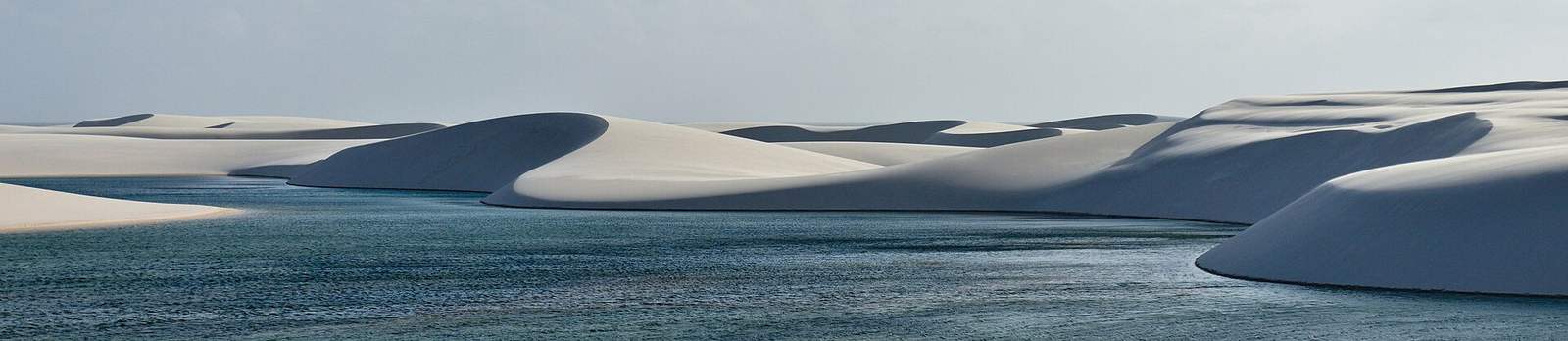 Panorámica de una laguna profunda serpenteando entre dunas blancas